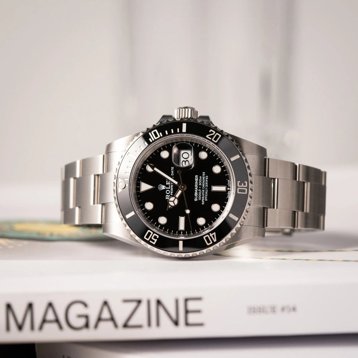 Produktfotografie der seitlich auf dem Uhrengehäuse liegenden Rolex Submariner Date 126610LN am Oyster-Stahlband im Neuzustand