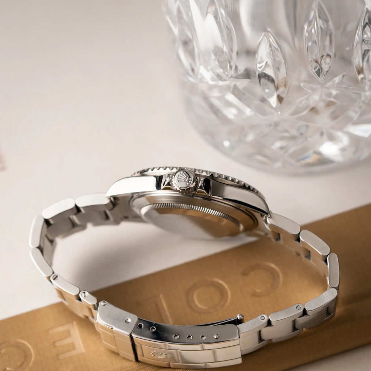 Produktfotografie zeigt das seitliche Gehäuse der Rolex Submariner Date 16610LV aus 2007 mit schwarzem Zifferblatt und der grünen "Kermit" Aluminium-Lünetten-Einlage mit Blick auf die Aufzugskrone