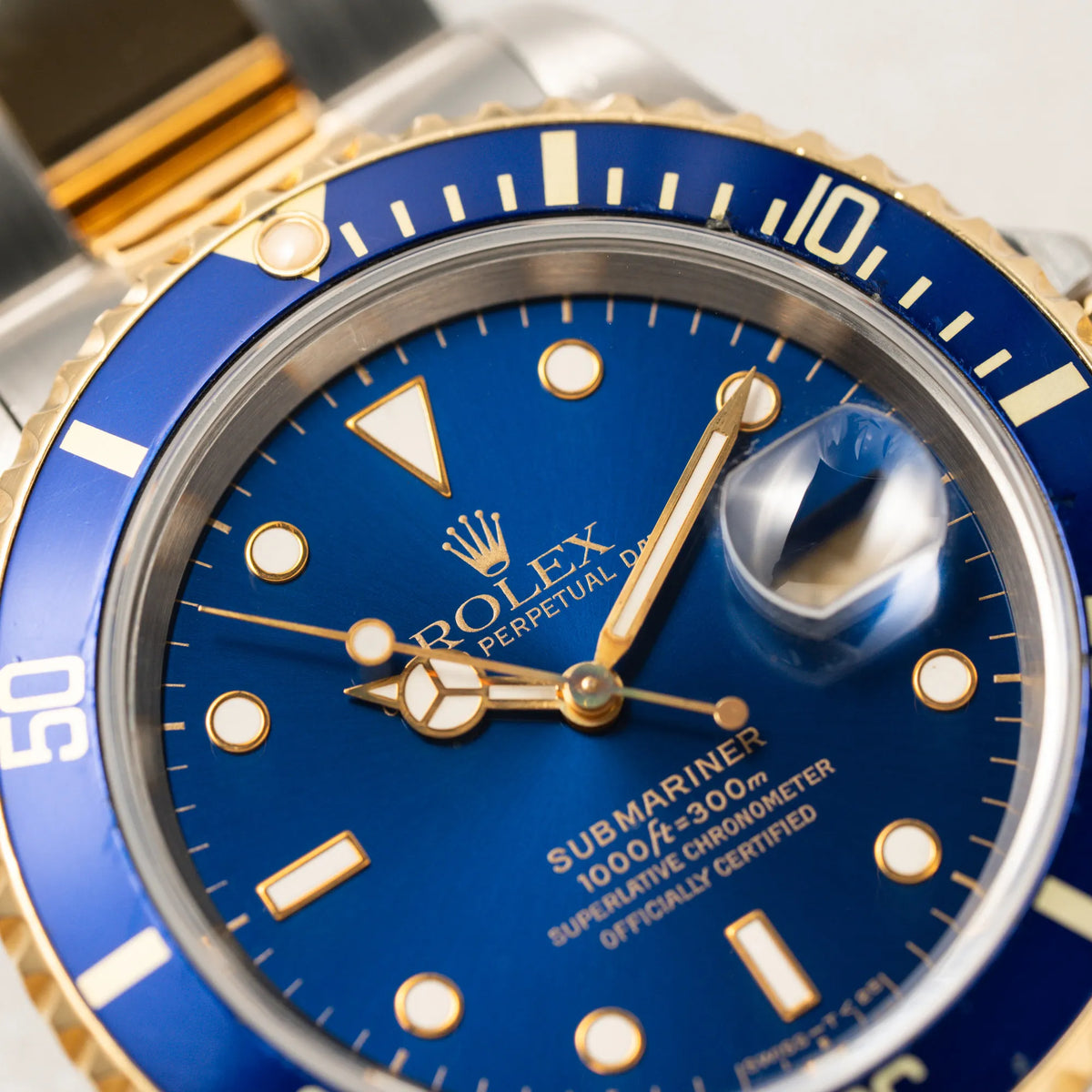 Makroaufnahme zeigt den goldenen Zeigersatz der bicolor Rolex Submariner Date der Referenz 16613 mit dem Spitznamen "Bluesy" in Stahl-Gold mit blauem Zifferblatt