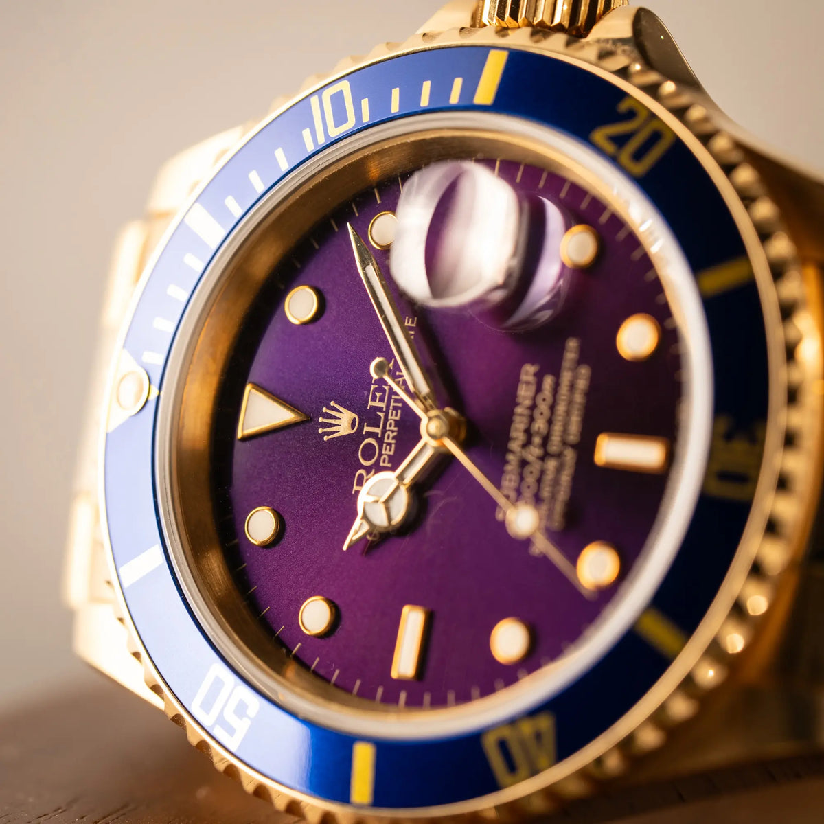 Makro-Aufnahme der Rolex Submariner Date 16618 aus 18Karat Gelbgold mit blauer Lünetten-Einlage und einem sich von BLAU zu LILA verfärbtem Purple-Zifferblatt
