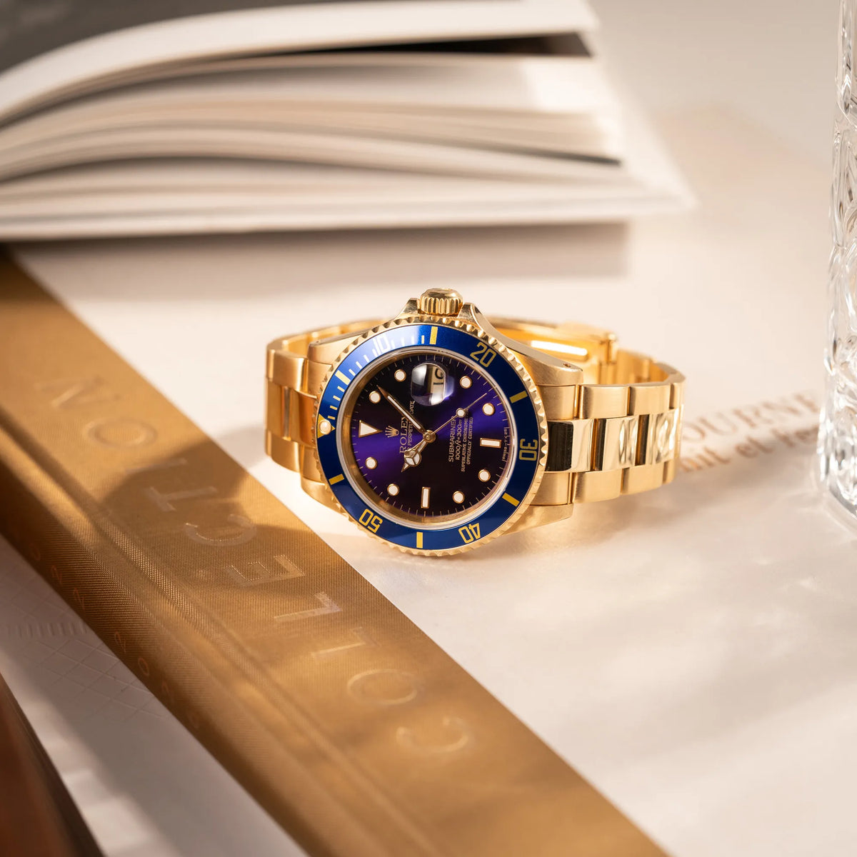 Produktfotografie der Rolex Submariner Date 16618 aus 18Karat Gelbgold mit blauer Lünetten-Einlage und einem sich von BLAU zu LILA verfärbtem Purple-Zifferblatt