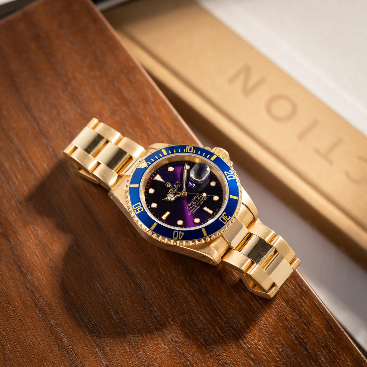 Produktfotografie der Rolex Submariner Date 16618 aus 18Karat Gelbgold mit blauer Lünetten-Einlage und einem sich von BLAU zu LILA verfärbtem Purple-Zifferblatt