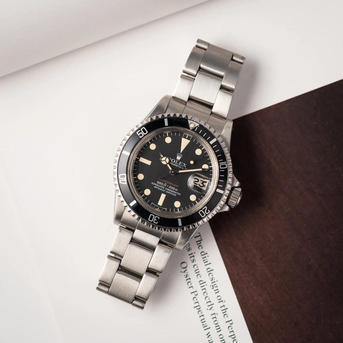 Rolex Submariner Date 1680 mit dem Submariner Red Schriftzug auf dem Mark V Zifferblatt mit schöner gleichmäßiger Patina bei den Zeigern und Indizes liegt flach auf dem Rolex-Magazin