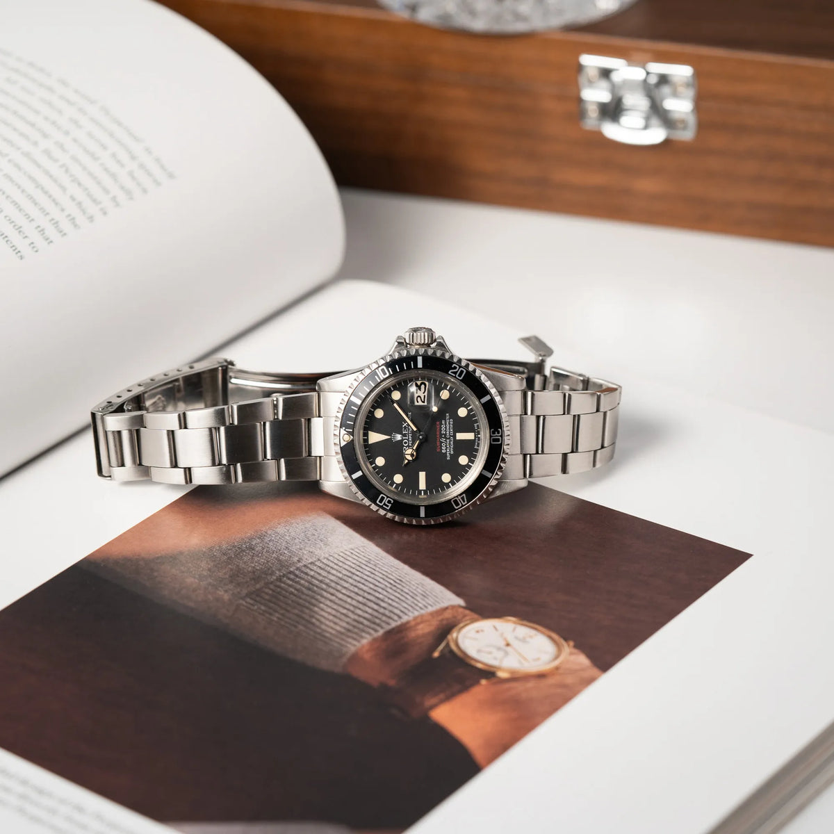 Rolex Submariner Date 1680 mit dem Submariner Red Schriftzug auf dem Mark V Zifferblatt mit schöner gleichmäßiger Patina bei den Zeigern und Indizes liegt seitlich auf dem Uhrengehäuse während die Oyster-Schliesse geöffnet ist