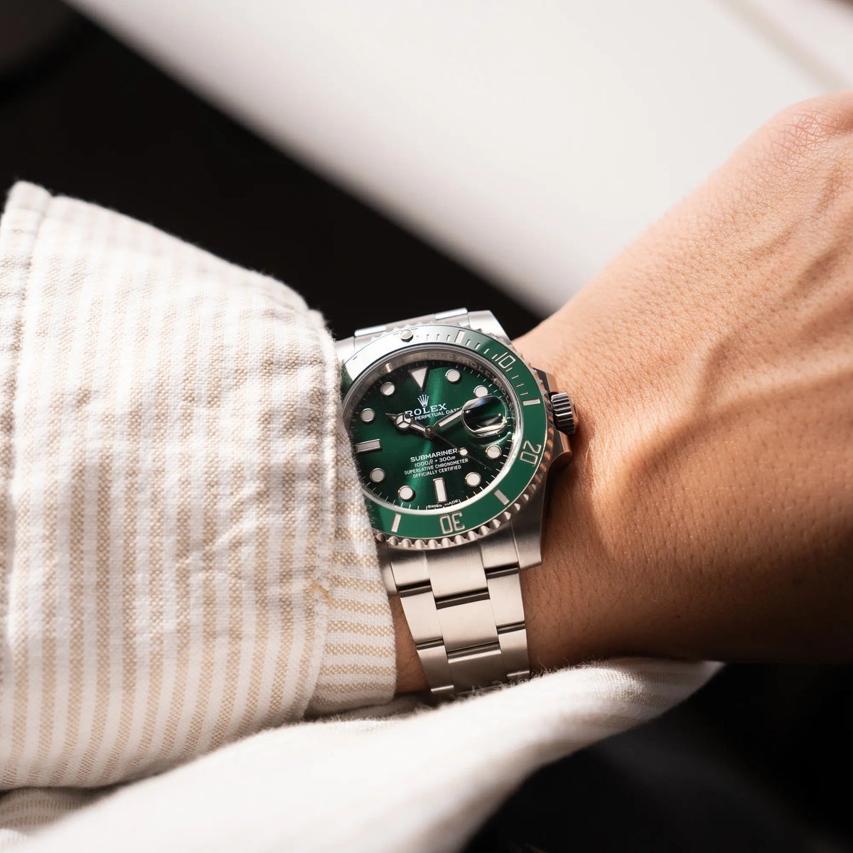 Mann trägt die Rolex Submariner Date 116610LV, Nickname "HULK", mit dem grünen Zifferblatt und der grünen Keramik-Lünette, an dem klassischen Oyster-Stahl-Armband, an seinem Handgelenk