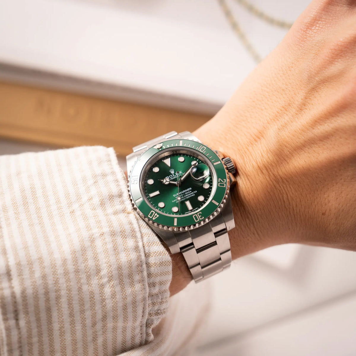 Mann trägt die Rolex Submariner Date 116610LV, Nickname "HULK", mit dem grünen Zifferblatt und der grünen Keramik-Lünette, an dem klassischen Oyster-Stahl-Armband an seinem Handgelenk