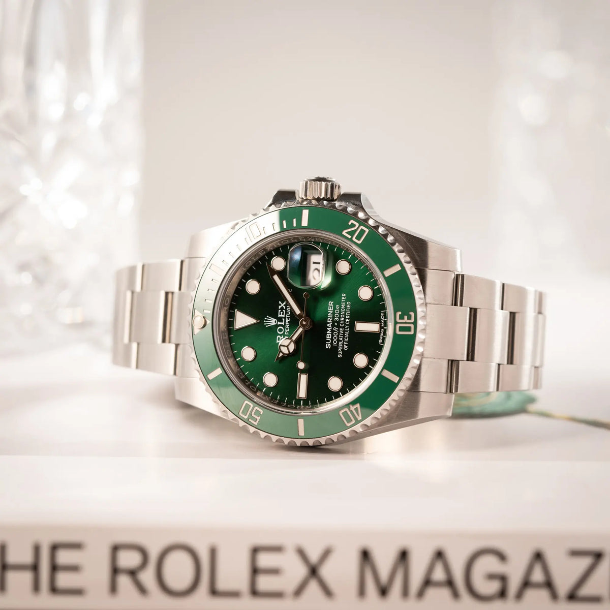 Produktfotografie der Rolex Submariner Date 116610LV, Nickname "HULK", mit dem grünen Zifferblatt und der grünen Keramik-Lünette, an dem klassischen Oyster-Stahl-Armband zeigt den Sonnenschliff des Zifferblatts mit verschiedenen Grün-Tönen