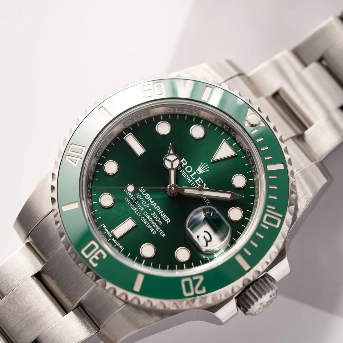 Detailaufnahme zeigt den Uhrenkopf der Rolex Submariner Date 116610LV, Nickname "HULK", mit dem grünen Zifferblatt und der grünen Keramik-Lünette, an dem klassischen Oyster-Stahl-Armband