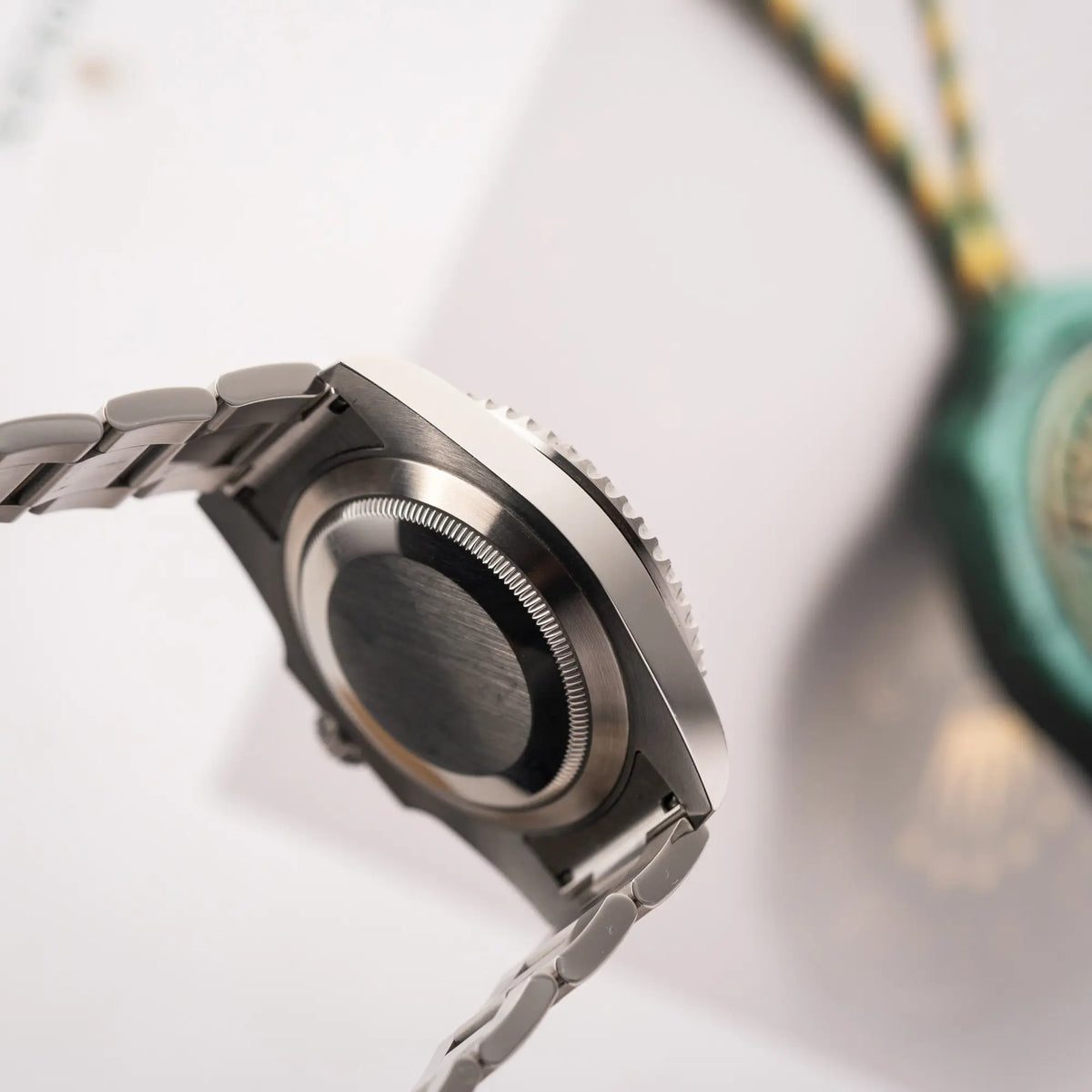 Produktfotografie der Rolex Submariner Date 116610LV, Nickname "HULK", mit dem grünen Zifferblatt und der grünen Keramik-Lünette, an dem klassischen Oyster-Stahl-Armband zeigt die seitliche Gehäuseflanke und den Gehäuseboden