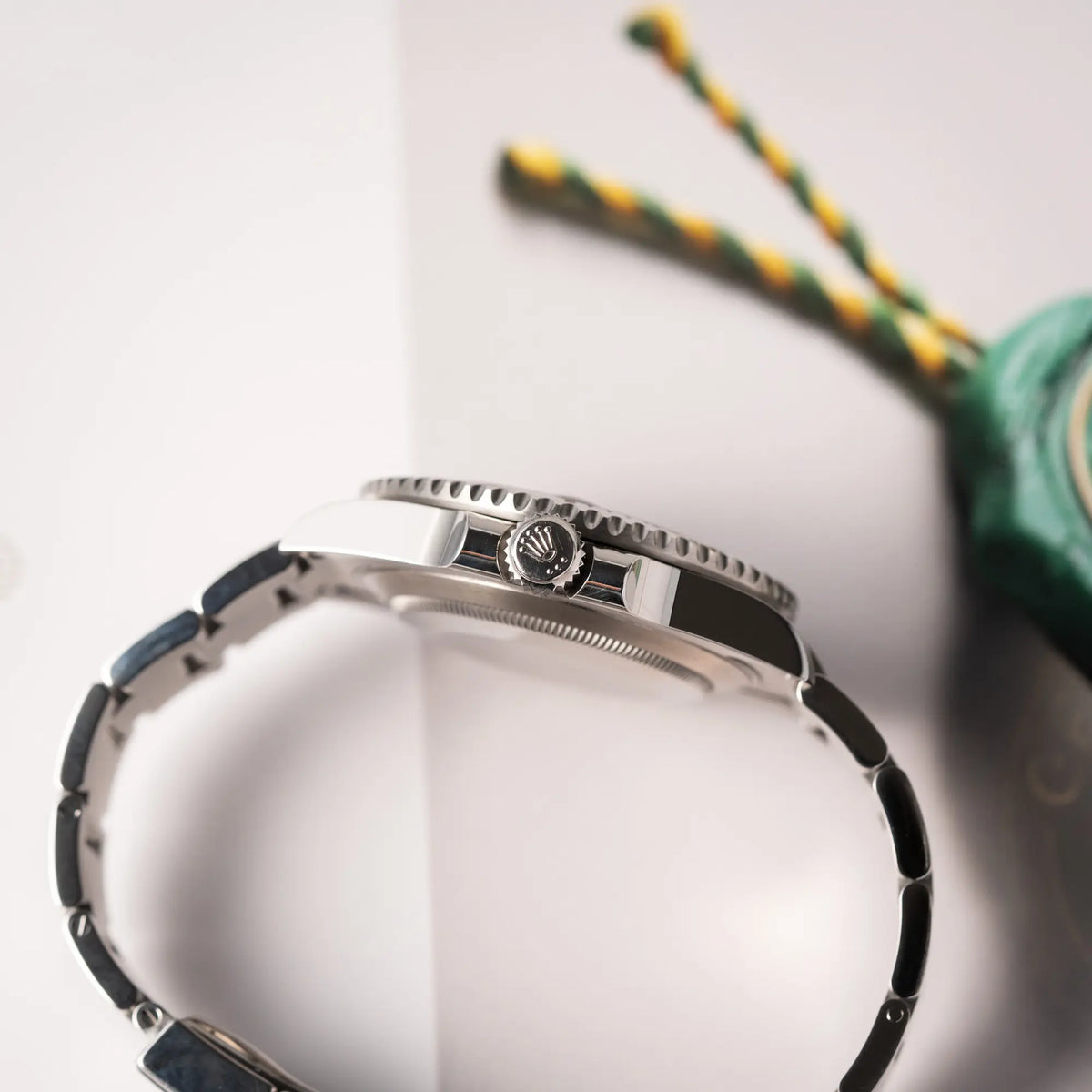 Seitliche Gehäuseflanke mit Blick auf die Aufzugskrone der Rolex Submariner Date 116610LV, Nickname "HULK", mit dem grünen Zifferblatt und der grünen Keramik-Lünette, an dem klassischen Oyster-Stahl-Armband