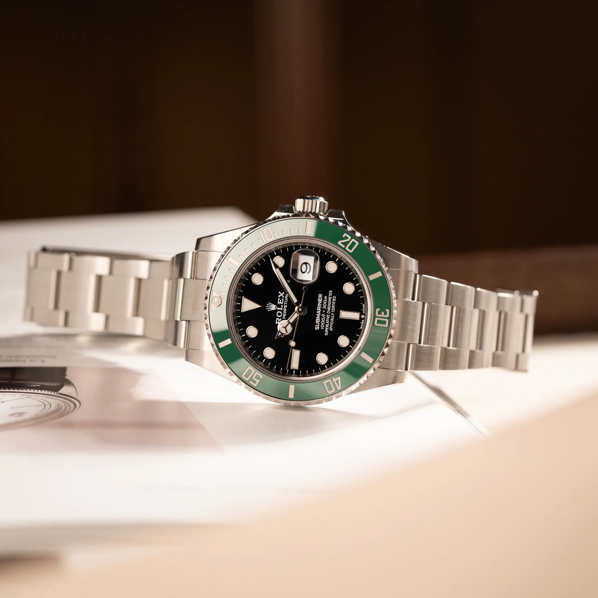 Produktfotografie der seitlich auf dem Uhrenkopf liegenden Rolex Submariner Date Starbucks 126610LV mit schwarzem Zifferblatt und grüner Cerachrom-Lünette
