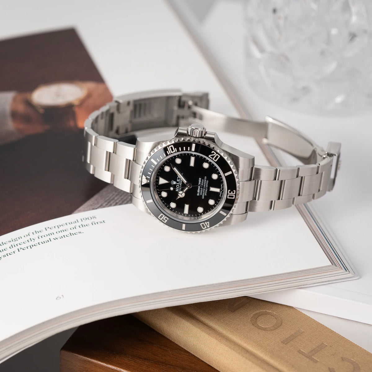 Produktfotografie der seitlich auf dem Uhrengehäuse liegenden Rolex Submariner 114060 No Date aus 2019 in der klassischen schwarzen Ausführung im Neuzustand