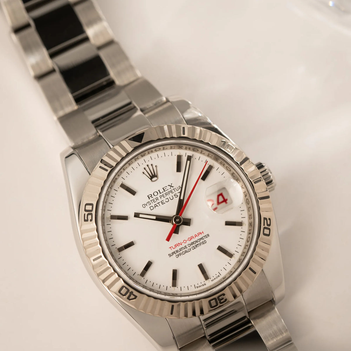 Produktfotografie der Rolex Datejust Turn-O-Graph 116264 in 36 mm mit dem weißen Zifferblatt und dem roten Sekundenzeiger mit Fokus auf dem Uhrenkopf