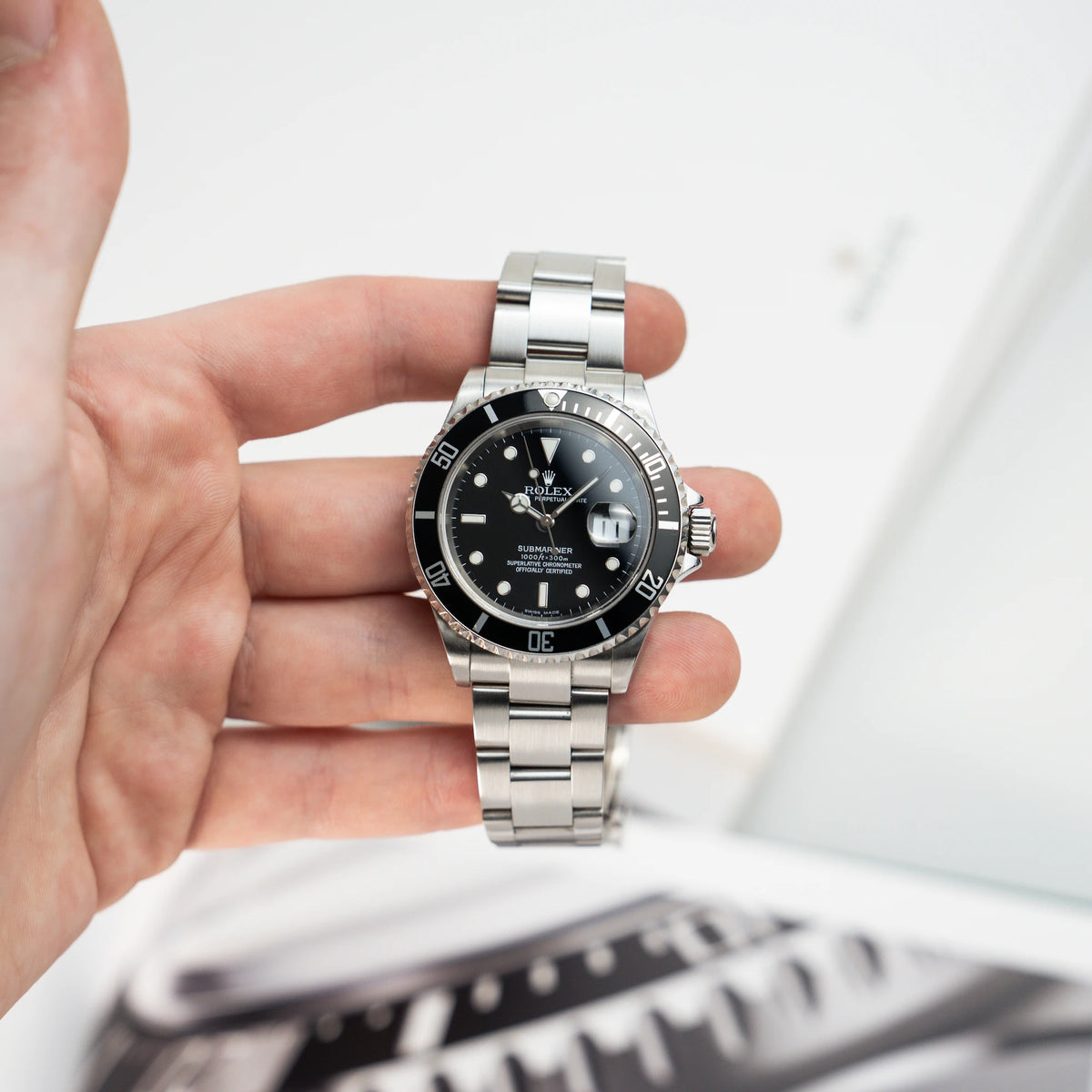 Mann hält die Rolex Submariner Date in Schwarz mit der Referenz 16610T in seiner Hand