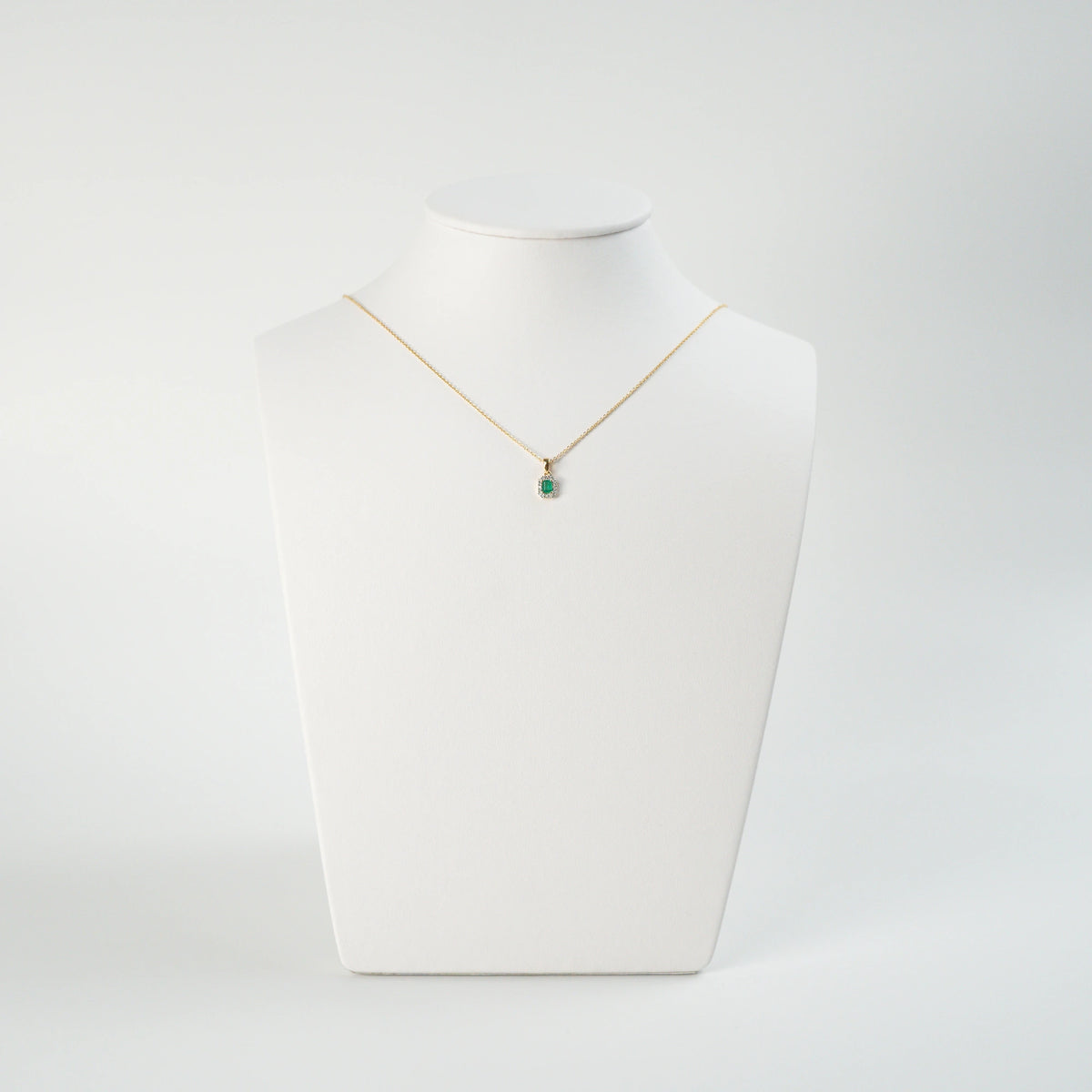 Smaragd Brillant Kette, bestehend aus einem Smaragd-Brillant Anhänger mit goldener Öse und einer goldenen feinen Kette aus der Schmuckatelier Lang Collection wird auf einer Büste präsentiert