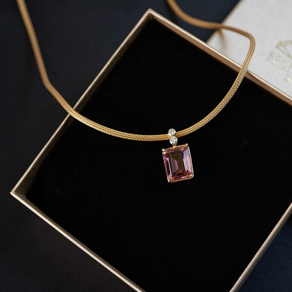 Gelbgoldenes Colliers aus der Schmuckatelier Lang Collection mit einem großen pinken Tansanit als Anhänger, das in der Umverpackung ohne Deckel liegt