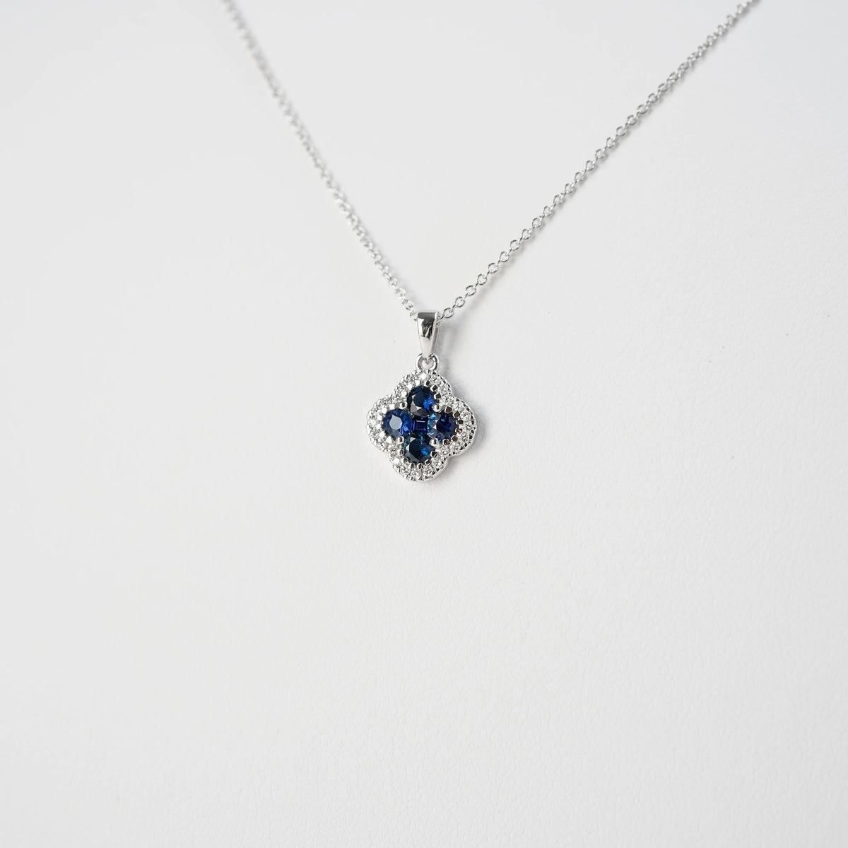 Detailaufnahme der Saphir Kleeblatt Kette aus Weißgold mit einem Saphir-Brillant-Anhänger in einer Kleeblatt-Form, bei dem die Saphire durch die kleinen Diamanten umrandet sind