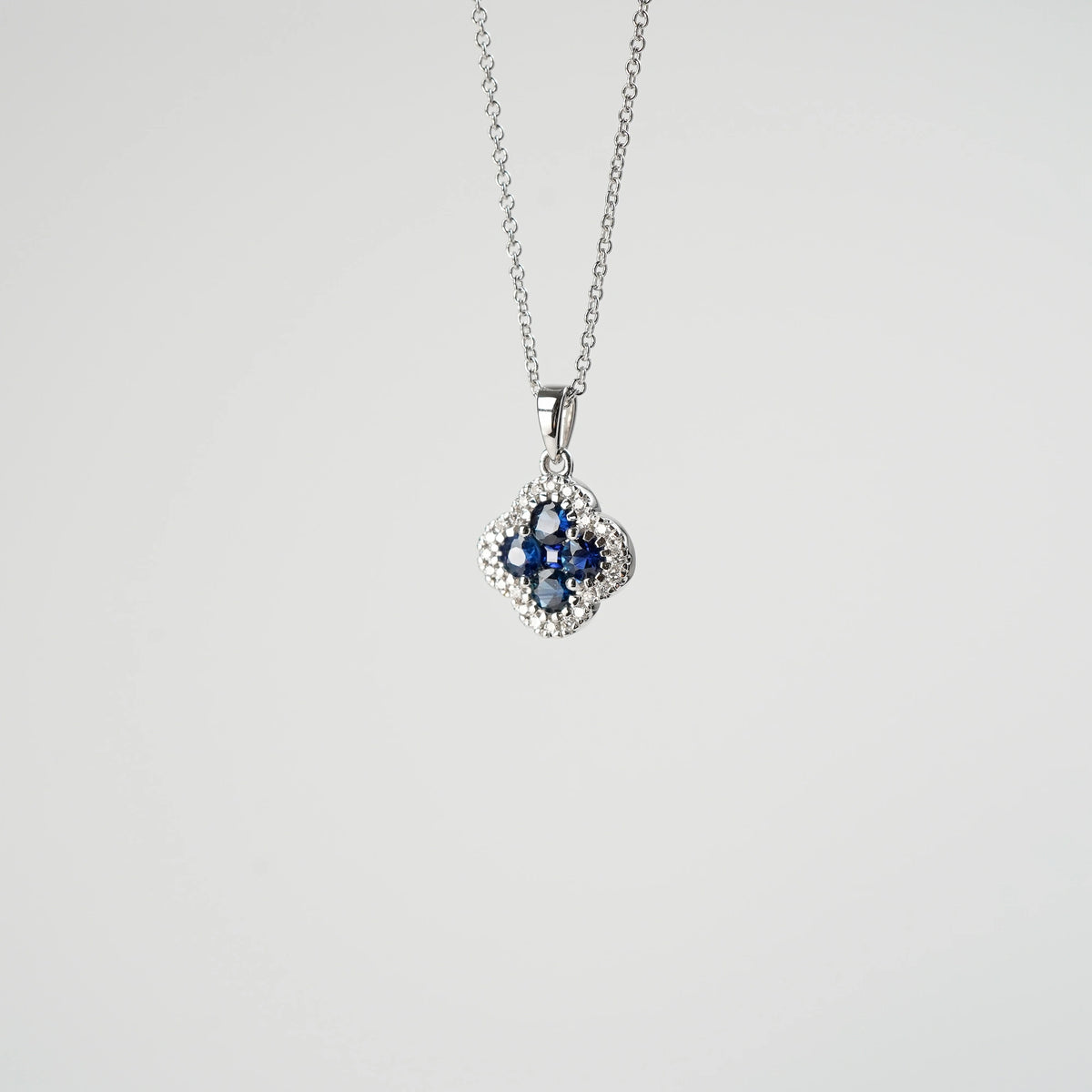 Saphir Kleeblatt Kette aus Weißgold mit einem Saphir-Brillant-Anhänger in einer Kleeblatt-Form, bei dem die Saphire durch die kleinen Diamanten umrandet sind, schwebt in der Luft