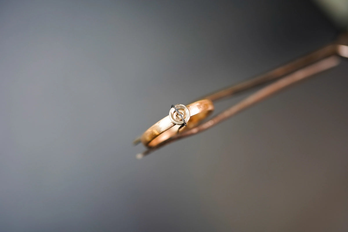 Goldschmied hält noch nicht fertigen Ring mit Pinzette
