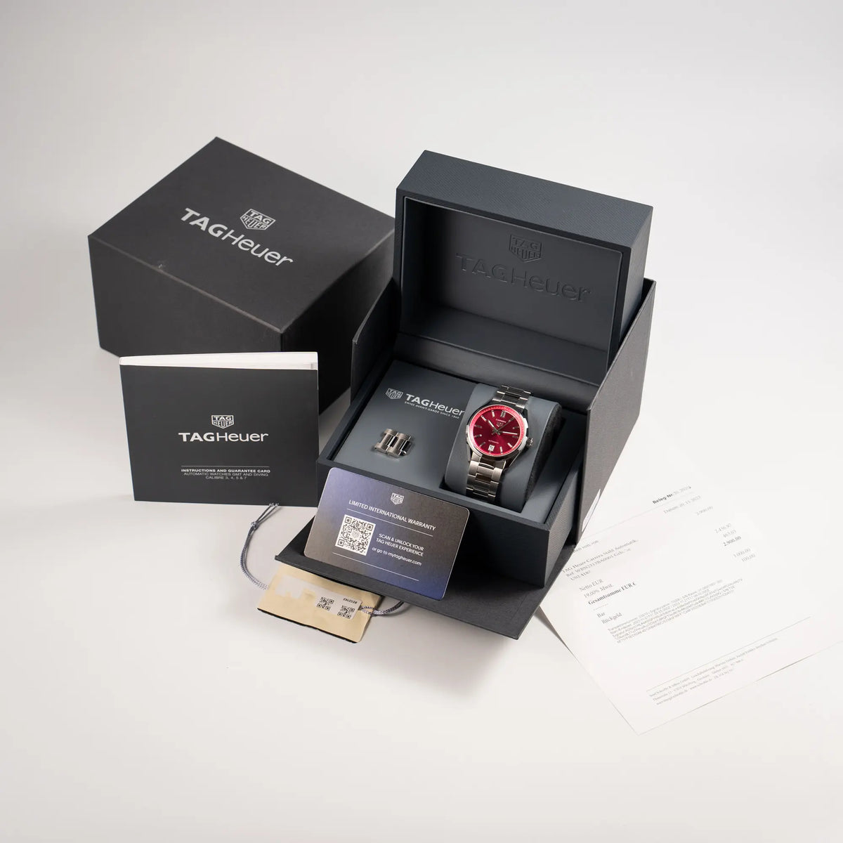 Lieferumfang zu der Tag Heuer Carrera Date Lady mit einem 36mm-Gehäuse und einem markanten pinken Zifferblatt mit Sonnenschliff-Finish, bestehend aus Box mit Umkarton, Garantiekarte, Booklets und Erstkaufrechnung