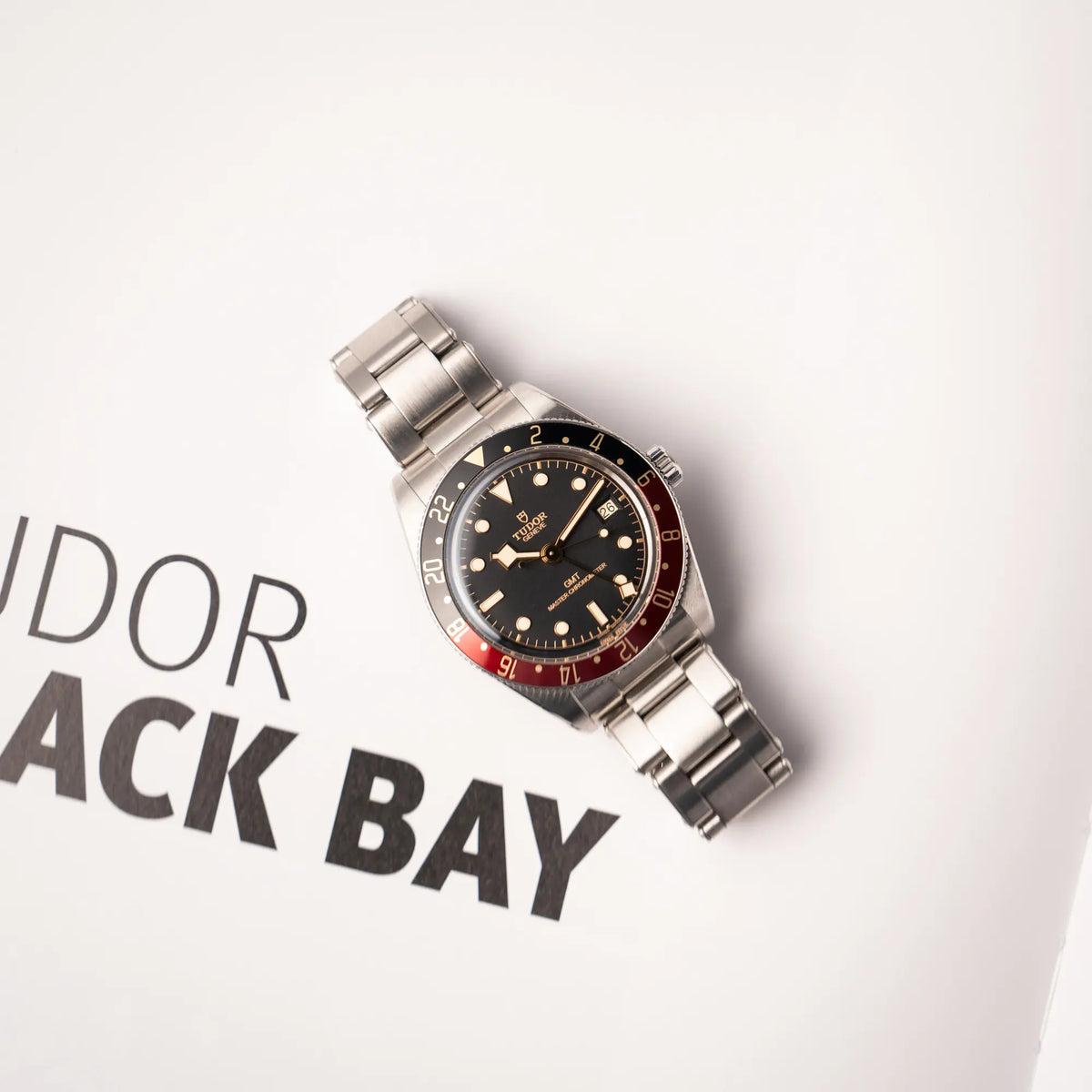 Produktfotografie zeigt die Tudor BlackBay GMT Coke der Referenz 7939G1A0NRU mit der schwarz-roten Lünette und bronzefarbenen Details am Edelstahlarmband aus der Vogelperspektive
