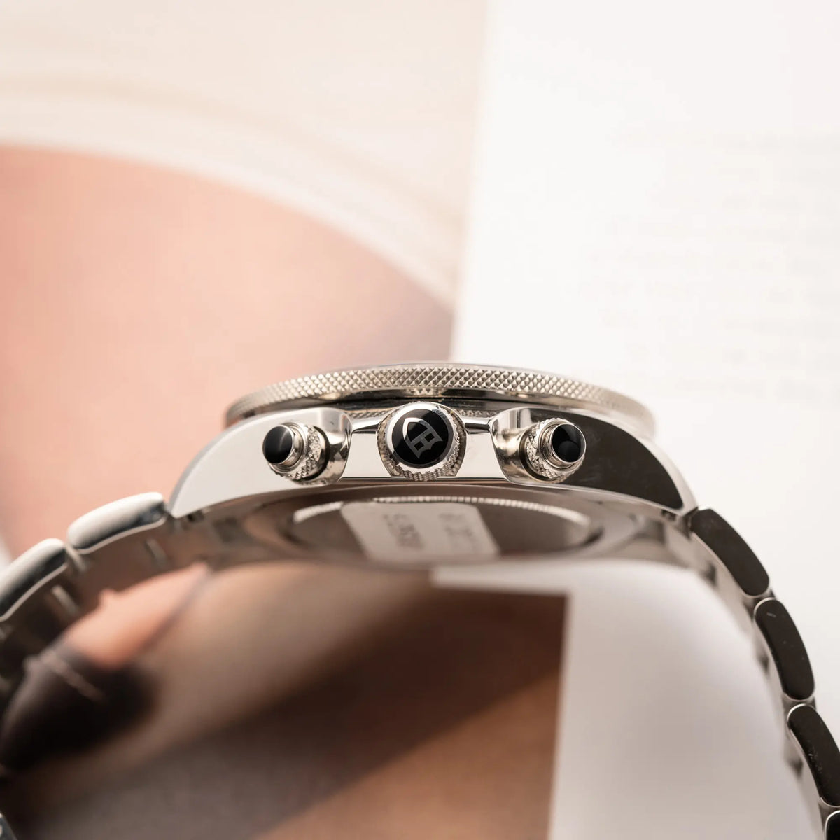 Seitliche Gehäuseflanke mit Blick auf die Aufzugskrone und die Chrono-Pusher von dem Tudor Black Bay Heritage Chronograph der Referenz 70330N mit schwarzem Zifferblatt und orangen Details