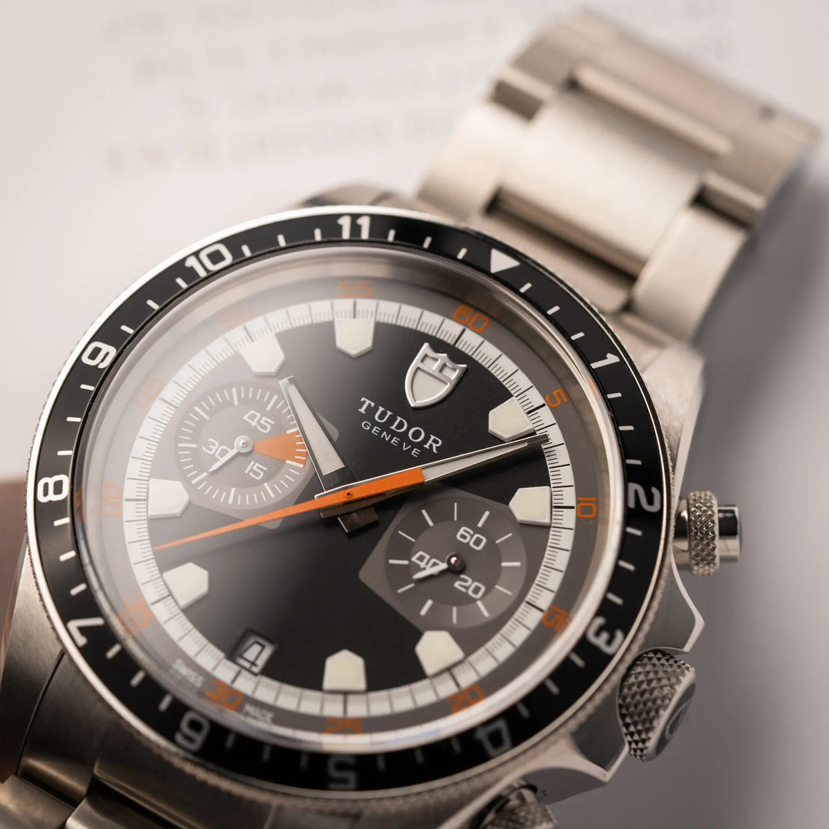 Detailaufnahme des Uhrenkopfes con dem Tudor Black Bay Heritage Chronograph der Referenz 70330N mit schwarzem Zifferblatt und orangen Details