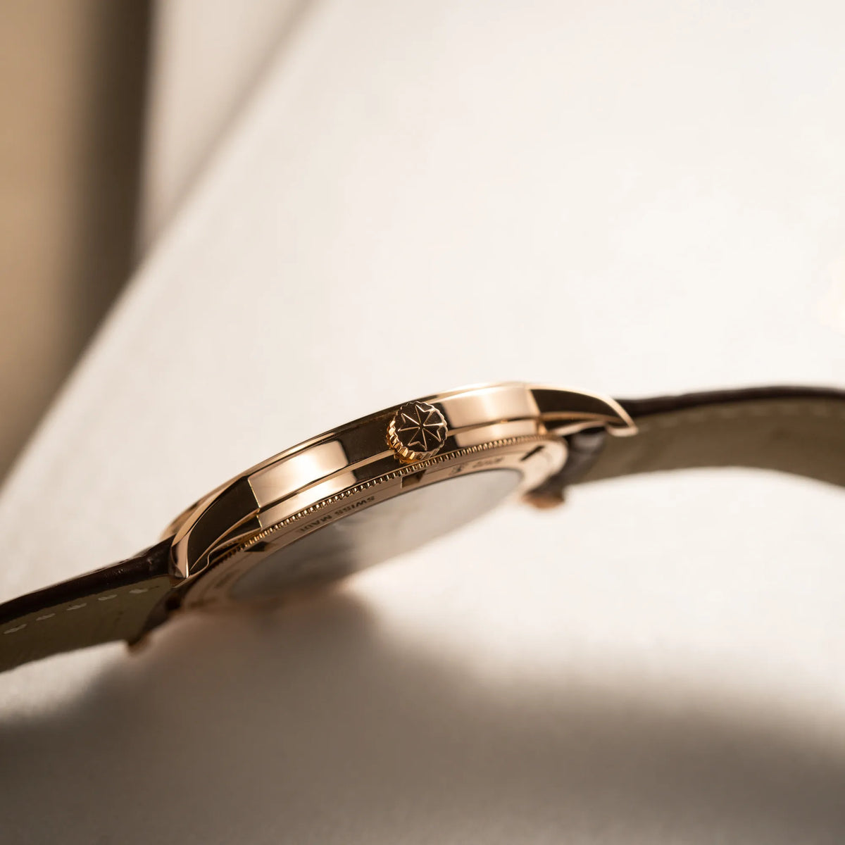 Produktfotografie zeigt das seitliche Gehäuse und die Aufzugskrone der Vacheron Constantin Patrimony 82172 in Roségold am braunem Lederband in einem nahezu neuwertigen Zustand