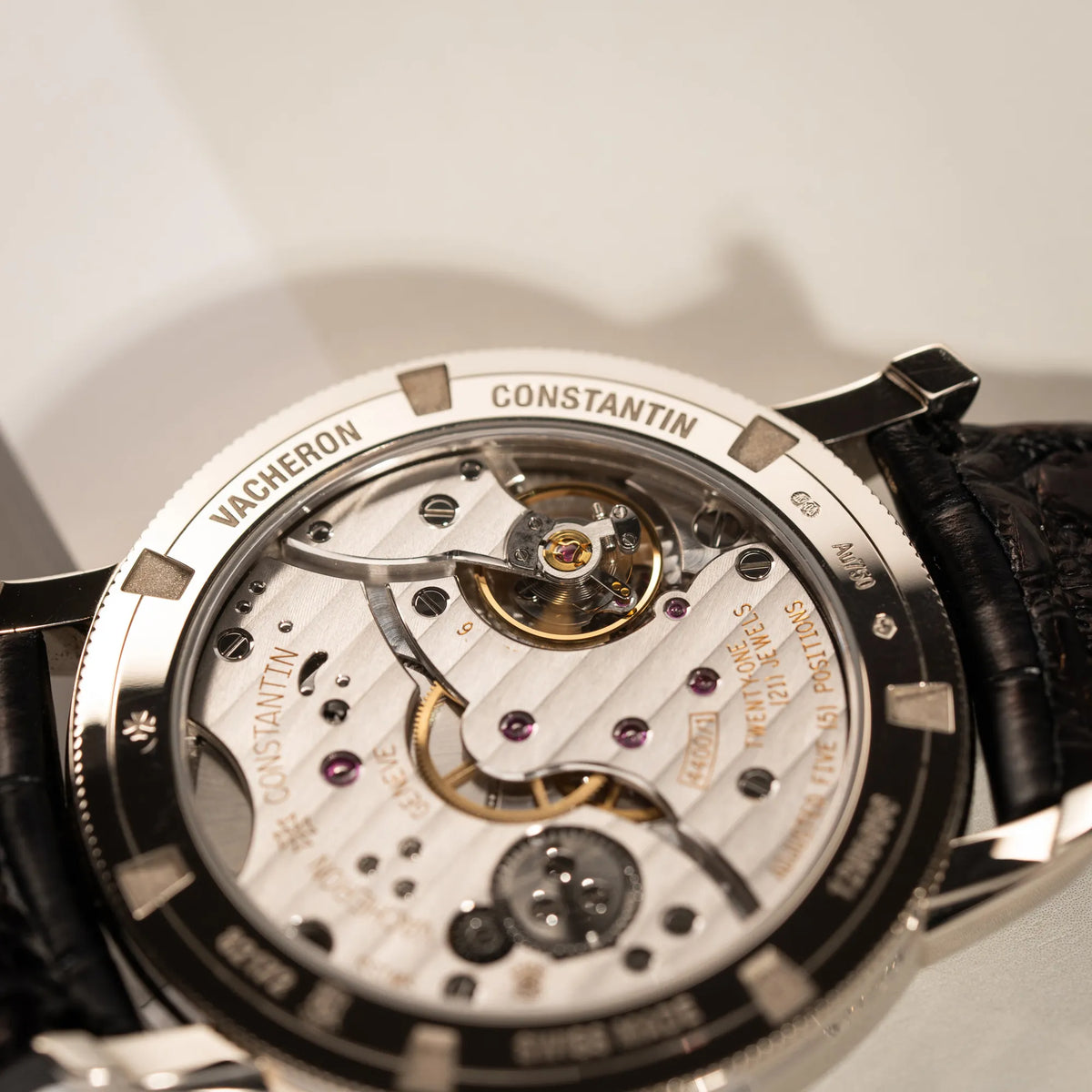 Produktfotografie zeigt das Handaufzugs-Caliber durch den Gehäuseboden mit Sichtglas von der Vacheron Constantin Traditionelle 82172 mit weißem Zifferblatt und einem Weißgold-Gehäuse am braunem Lederband