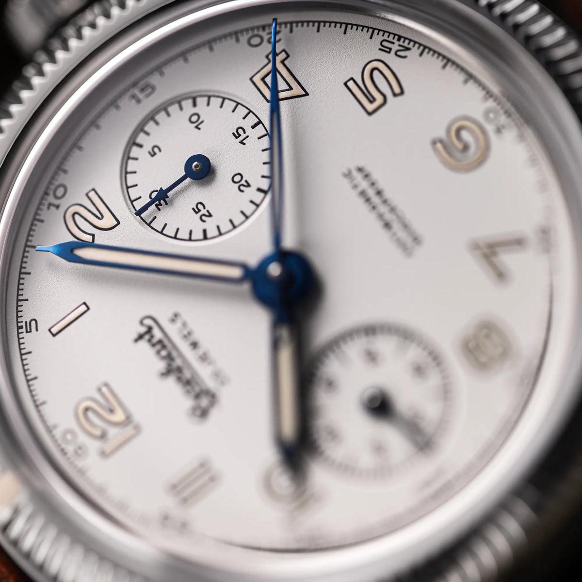 Detailaufnahme der Hanhart 417 ES Moby Dick mit weißem Zifferblatt und gebläuten Zeigern im 39 mm-Gehäuse am Edelstahlarmband mit Fokus auf dem Hilfszifferblatt für den Minutenzähler