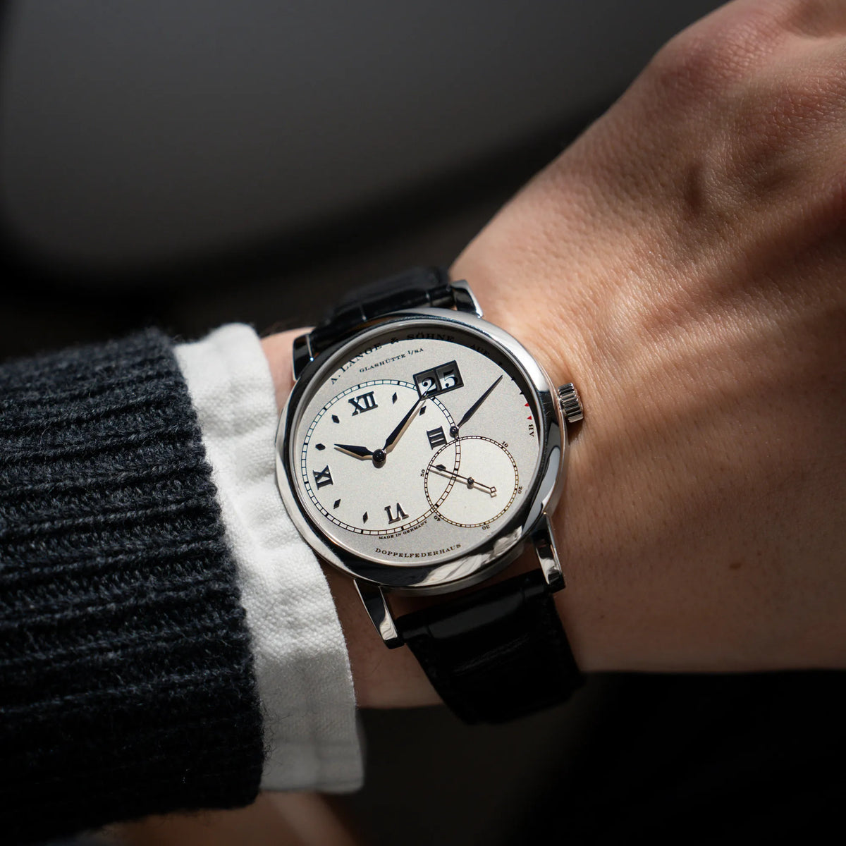 Wristshot mit der Großen Lange 1 mit Platingehäuse und silberfarbenem Zifferblatt am schwarzen Lederband von A. Lange & Söhne