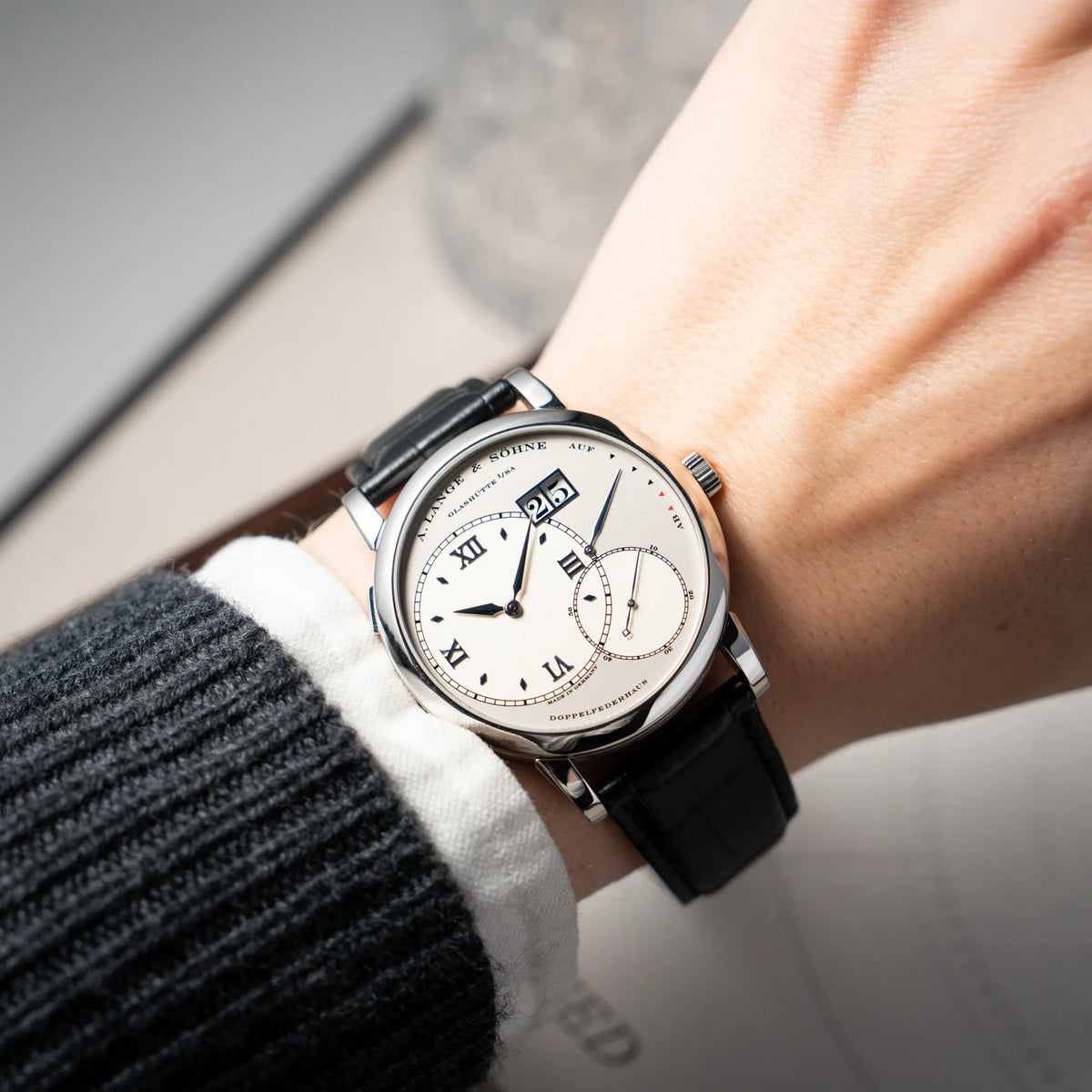 Wristshot mit der Großen Lange 1 mit Platingehäuse und silberfarbenem Zifferblatt am schwarzen Lederband von A. Lange & Söhne