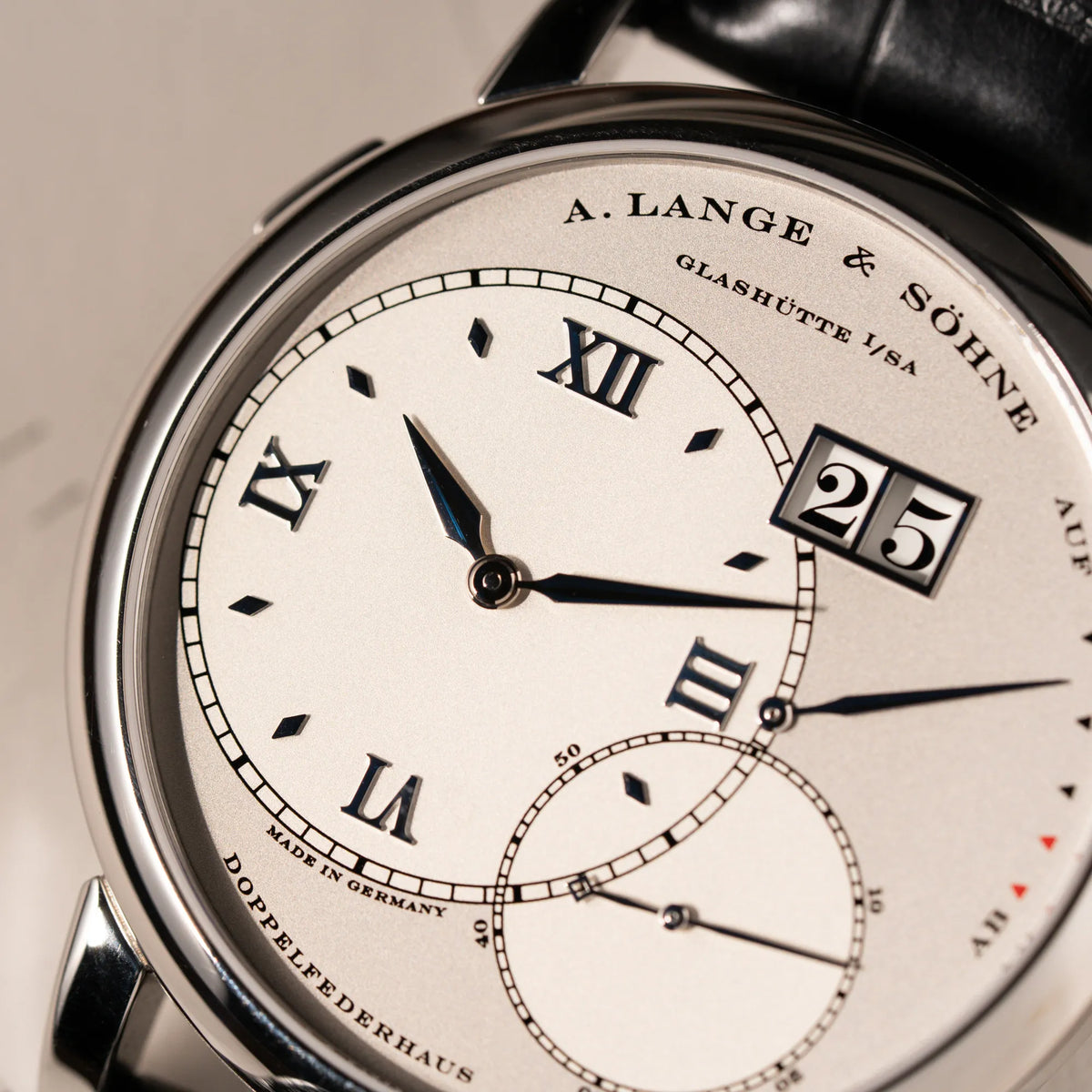 Detailaufnahme des Zifferblatts der Großen Lange 1 mit Platingehäuse und silberfarbenem Zifferblatt am schwarzen Lederband von A. Lange & Söhne