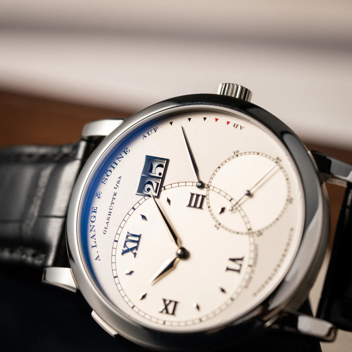Detailaufnahme der Großen Lange 1 mit Platingehäuse und silberfarbenem Zifferblatt am schwarzen Lederband von A. Lange & Söhne