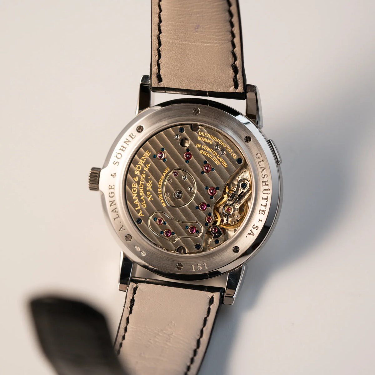 Gehäuseboden mit Sichtglas auf das Handaufzugskaliber der Großen Lange 1 mit Platingehäuse und silberfarbenem Zifferblatt am schwarzen Lederband von A. Lange & Söhne