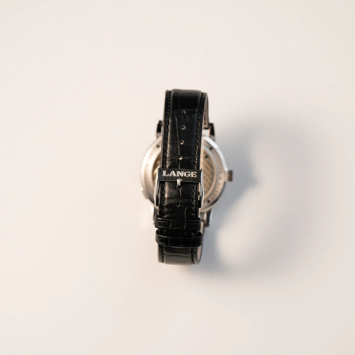 Blick auf das schwarze Lederband mit originaler A. Lange & Söhne Schliesse von der der Großen Lange 1 mit Platingehäuse und silberfarbenem Zifferblatt am schwarzen Lederband von A. Lange & Söhne