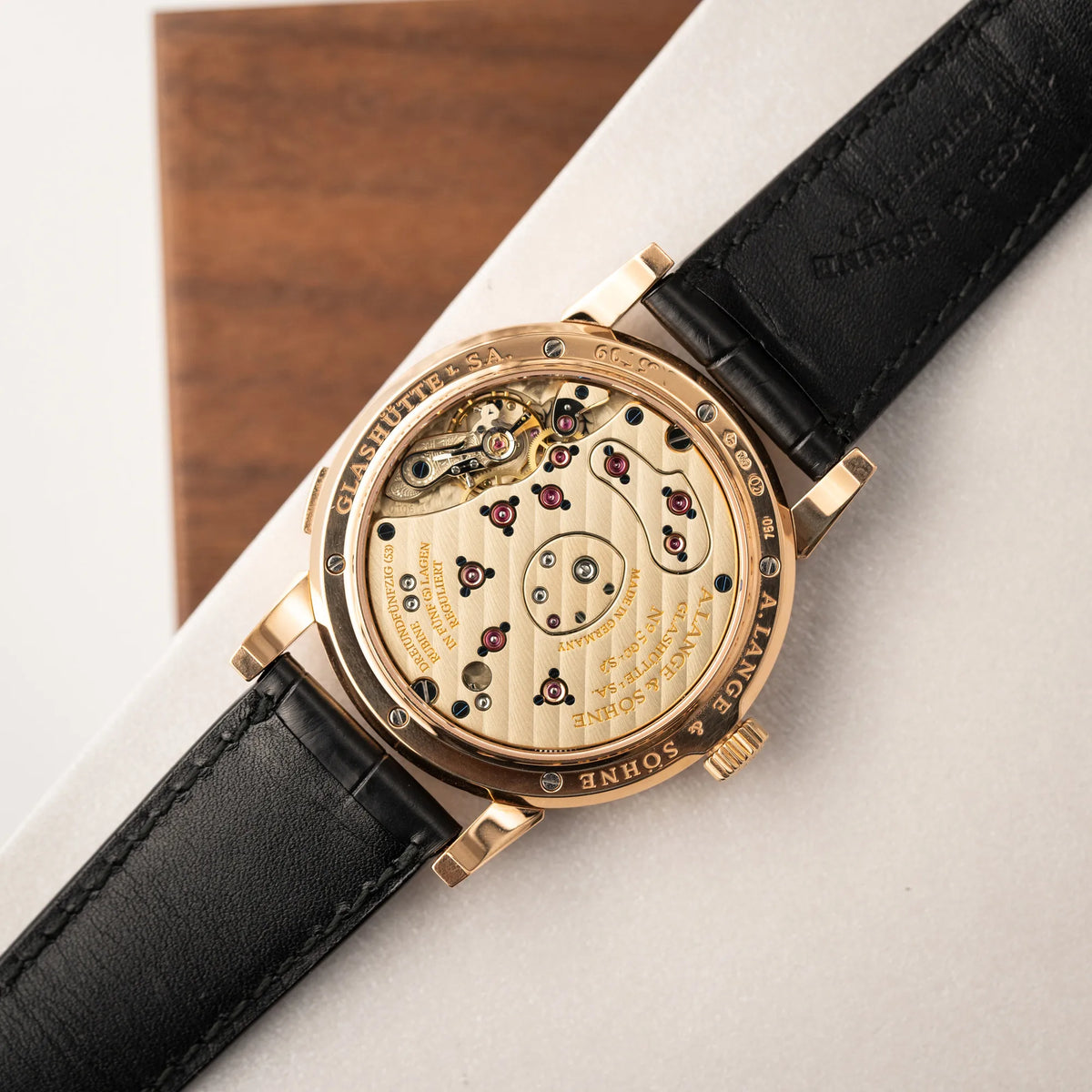Produktfotografie der A. Lange & Söhne Lange 1 der Referenz 101.032 mit 38,5mm-Roségold-Gehäuse und dem für das Modell typische, asymmetrisch angeordnete Zifferblatt mit Großdatum zeigt den Gehäuseboden mit Sichtglas 