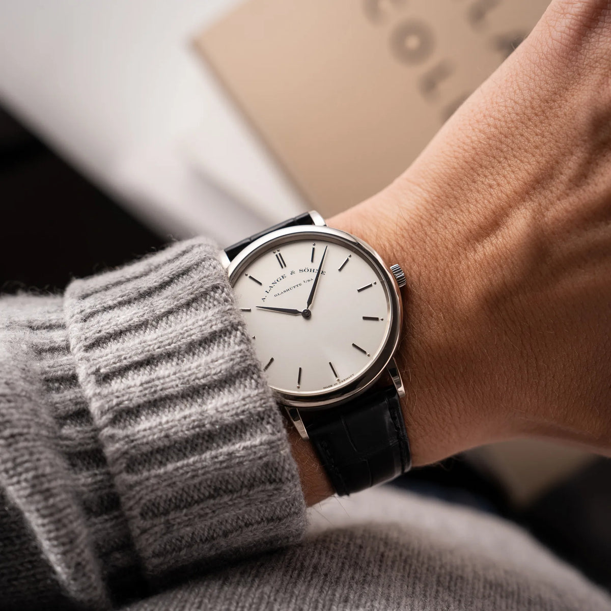 Mann trägt die A.Lange Söhne Saxonia Thin der Referenz 211.026 im Weißgold-Gehäuse mit weiß-silbernem Zifferblatt am schwarzen Lederarmband an seinem Handgelenk