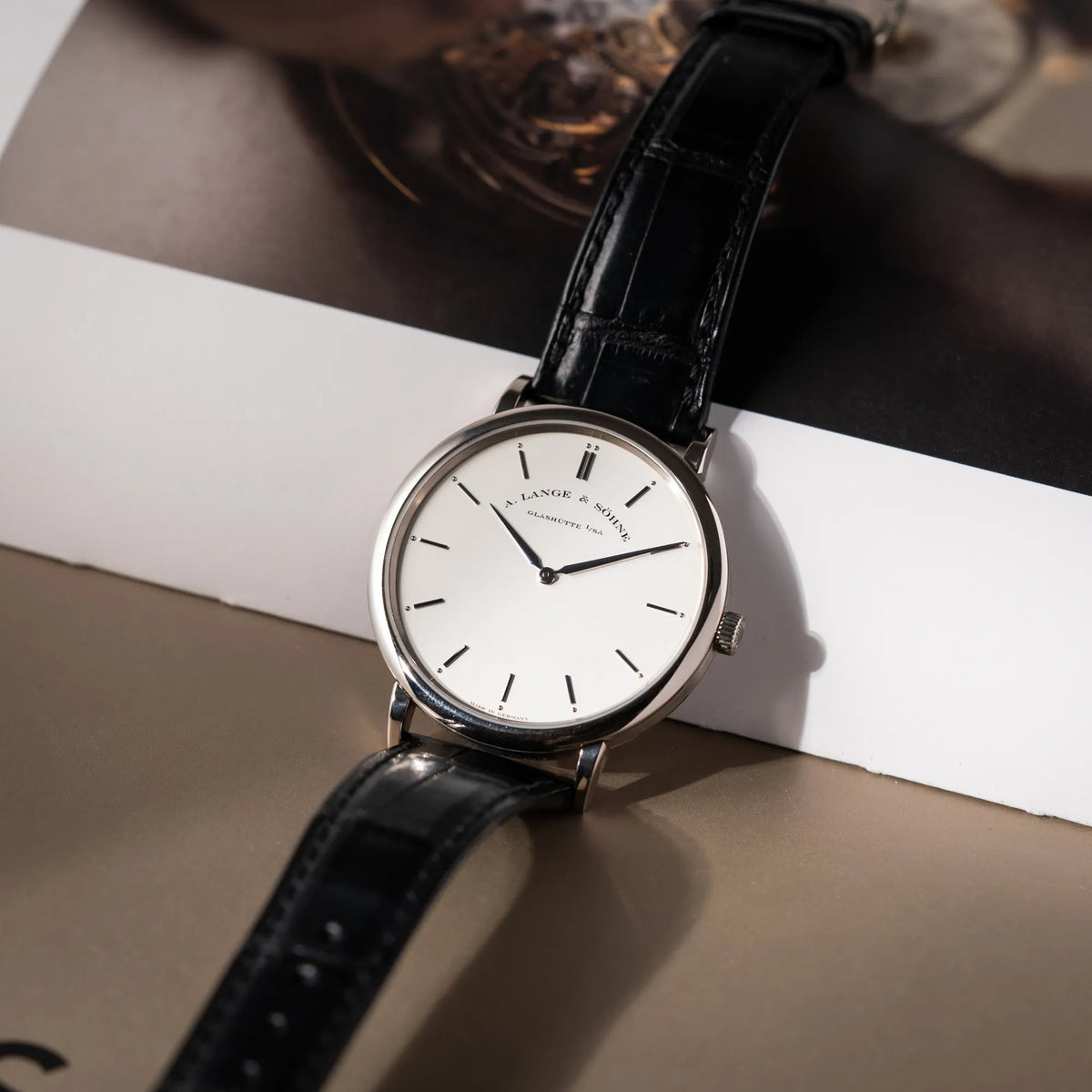 Produktfoto der A.Lange Söhne Saxonia Thin der Referenz 211.026 im Weißgold-Gehäuse mit weiß-silbernem Zifferblatt am schwarzen Lederarmband