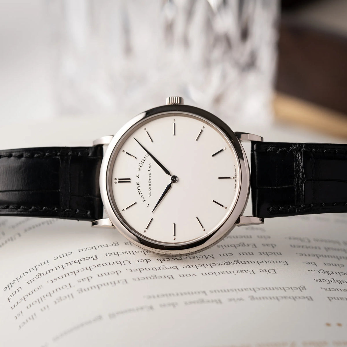 Produktfotografie der A.Lange Söhne Saxonia Thin der Referenz 211.026 im Weißgold-Gehäuse mit weiß-silbernem Zifferblatt am schwarzen Lederarmband