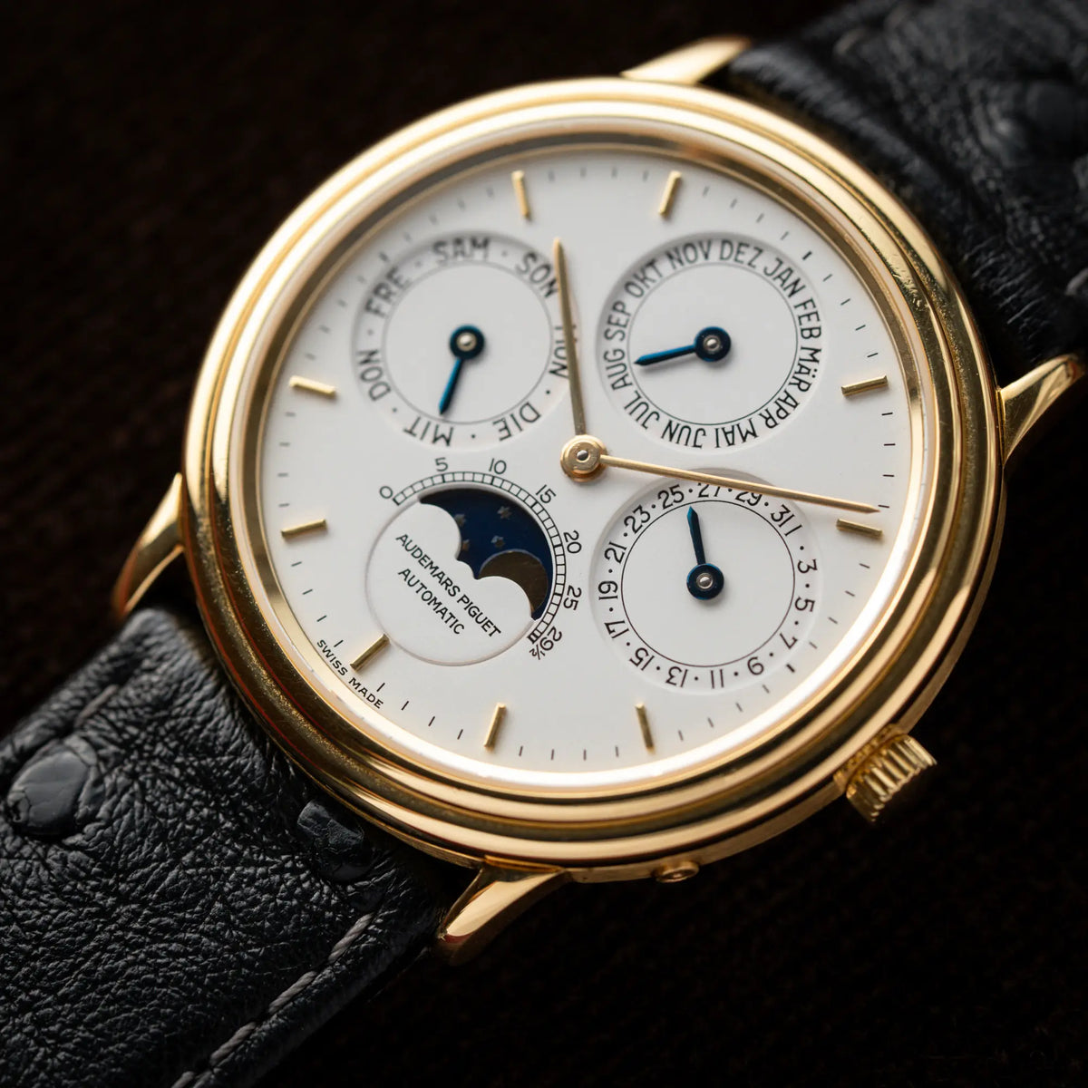Nahe Produktfotografie der Audemars Piguet Quantième Perpétual der Referenz 5548BA mit 36mm-Gelbgold-Gehäuse und weißem Zifferblatt an einem schwarzen Lederband