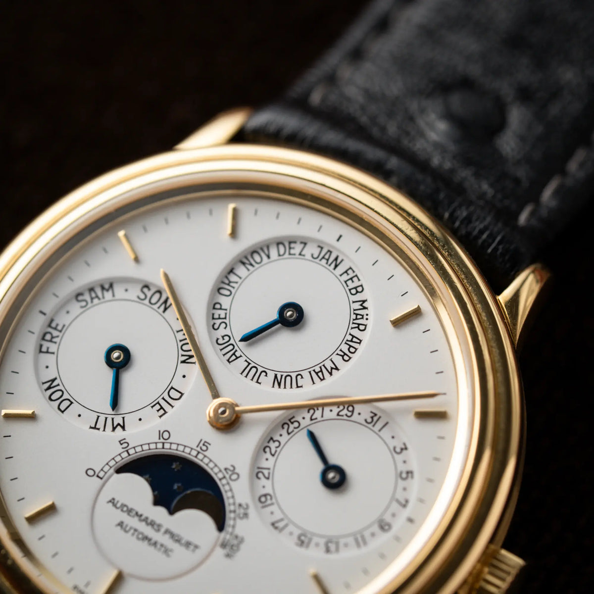 Detailaufnahme der Audemars Piguet Quantième Perpétual der Referenz 5548BA mit 36mm-Gelbgold-Gehäuse und weißem Zifferblatt an einem schwarzen Lederband mit Fokus auf dem Montasanzeige