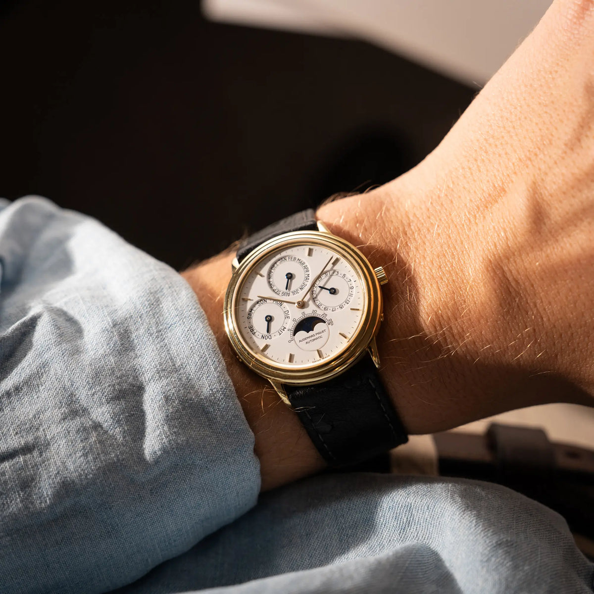 Wristshot mit der Audemars Piguet Quantième Perpétual der Referenz 5548BA mit 36mm-Gelbgold-Gehäuse und weißem Zifferblatt an einem schwarzen Lederband an einem Männerhandgelenk