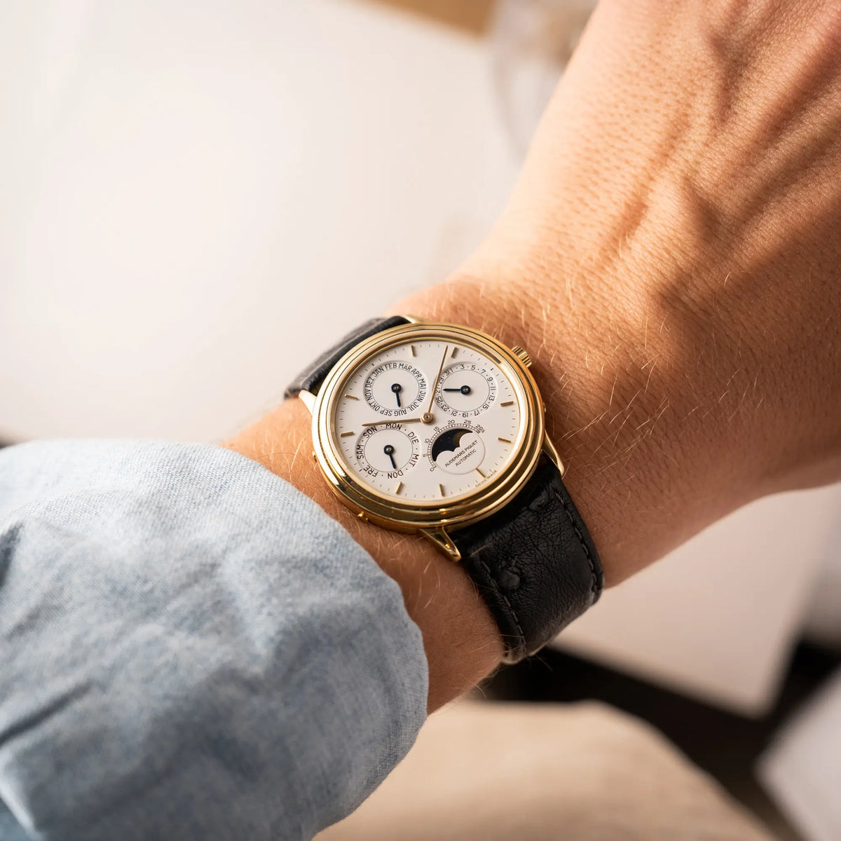 Mann trägt die Audemars Piguet Quantième Perpétual der Referenz 5548BA mit 36mm-Gelbgold-Gehäuse und weißem Zifferblatt an einem schwarzen Lederband an seinem Handgelenk