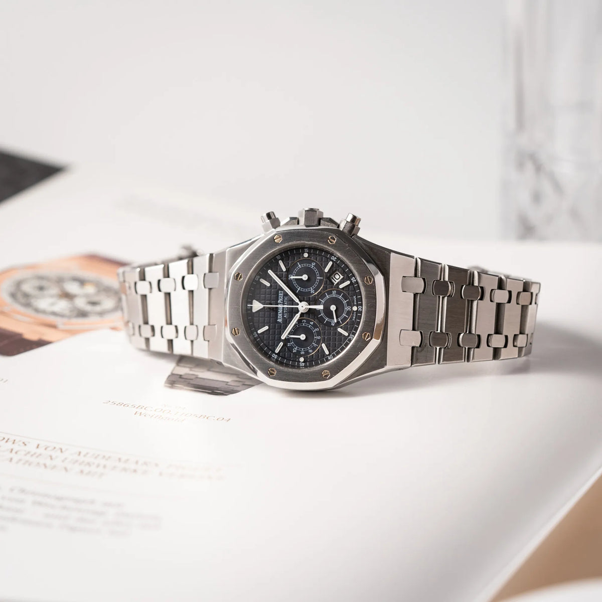  Audemars Piguet Royal Oak Chronograph Kasparov der Referenz 25860ST.mit blauem Tapisserie-Zifferblatt im 39mm-Edelstahl-Gehäuse liegt auf einem Uhrenbuch