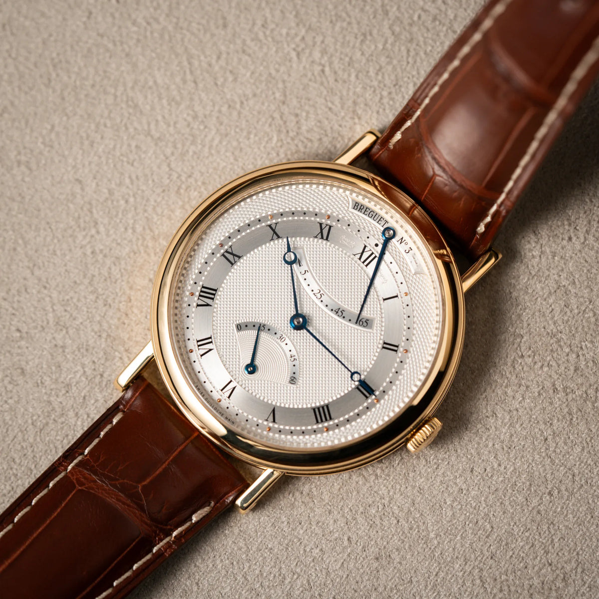 Detailaufnahme der gelbgoldenen Breguet Armbanduhr des Models Classic Retrograde 5207 am braunen Lederband