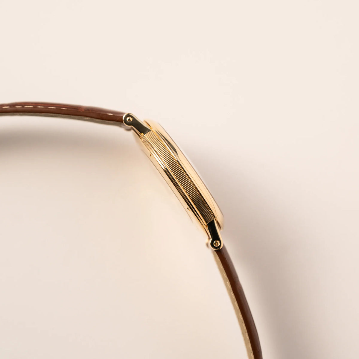 Seitliches Gehäuse der gelbgoldenen Breguet Armbanduhr des Models Classic Retrograde 5207 am braunen Lederband