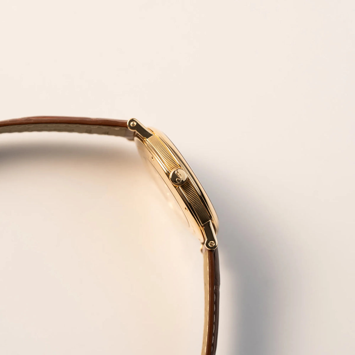 Seitliches Gehäuse der gelbgoldenen Breguet Armbanduhr des Models Classic Retrograde 5207 am braunen Lederband mit Blick auf die Aufzugskrone