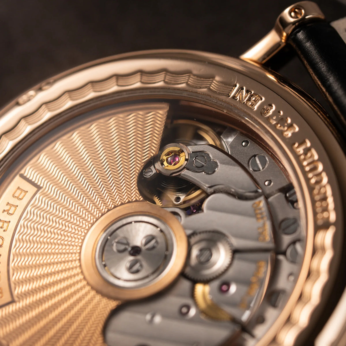 Detailaufnahme des Automatikuhrwerks durch den gläsernen Sichtboden der Breguet Classique 5177 in Roségold mit weißem Emaille-Zifferblatt