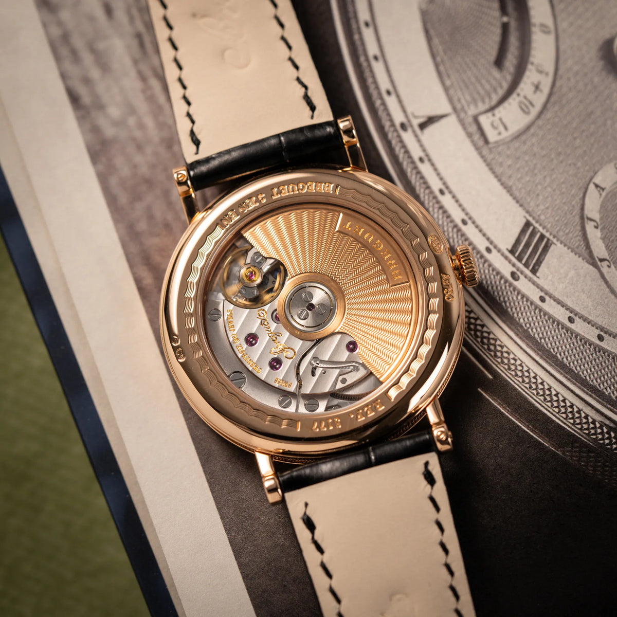 Produktfotografie der Breguet Classique 5177 in Roségold mit weißem Emaille-Zifferblatt zeigt das Automatikuhrwerk durch den Gehäuseboden mit Sichtglas